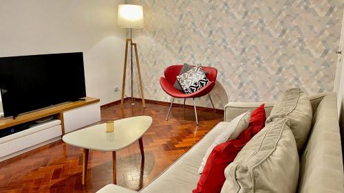 un soggiorno con divano, TV e sedia rossa di Mdz Apartments a Mendoza