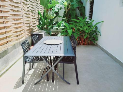 a blue table and chairs on a balcony with plants at Le DAMOUR Appartement 1 ou 2 chambres in Les Anses-dʼArlets