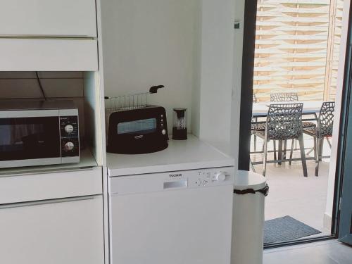 a kitchen with a microwave and a table with chairs at Le DAMOUR Appartement 1 ou 2 chambres in Les Anses-dʼArlets