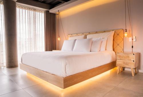 a bedroom with a large white bed with lights on it at Topá House in Medellín