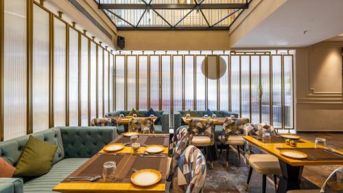 a restaurant with tables and chairs and large windows at Renest Calangute Goa in Calangute