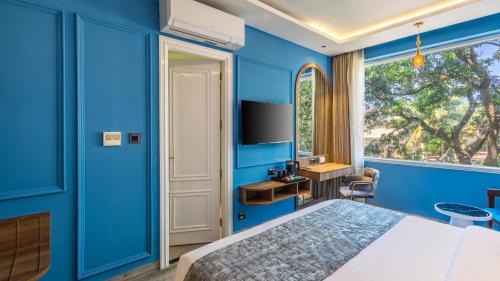a blue bedroom with a bed and a window at Renest Calangute Goa in Calangute