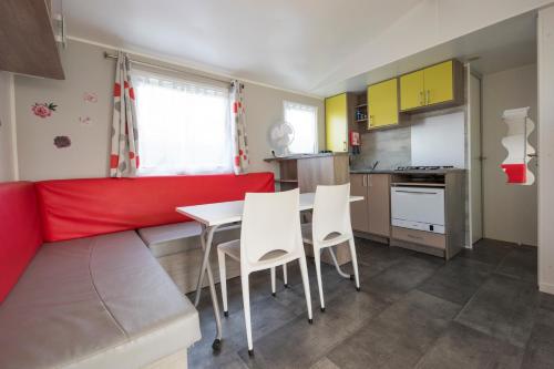 une cuisine avec un canapé rouge, une table et des chaises dans l'établissement le 934 des charmettes, aux Mathes