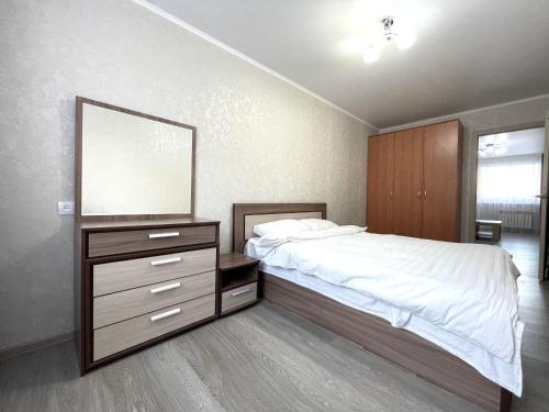a bedroom with a bed with a mirror and a dresser at Двухкомнатная квартира, новый ремонт, 2 этаж, центр in Petropavlovsk