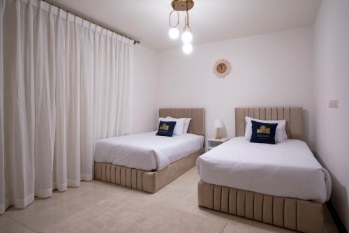 two beds in a room with white curtains at LOFTS by Elegant Hospitality in Cairo