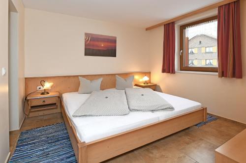 1 dormitorio con 1 cama con sábanas blancas y ventana en Tre Soli Appartements Restaurant, en Schoppernau