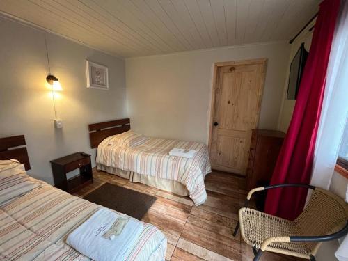 um quarto com duas camas e uma cadeira e uma porta em Hotel Restaurante Aconcagua em La Ligua
