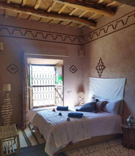 a bedroom with a large white bed and a window at Maison d'hôtes IZZA in Kalaat MGouna