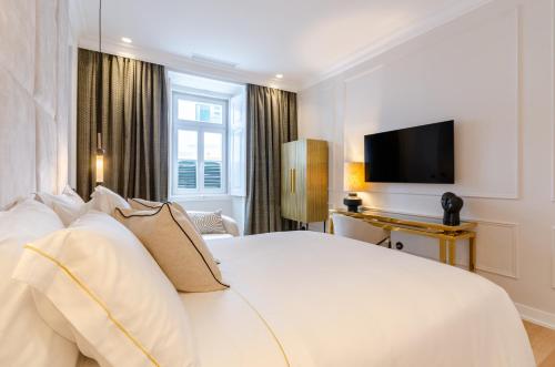 a hotel room with a white bed and a television at BCascais Boutique House by APT IIN Cascais Center in Cascais