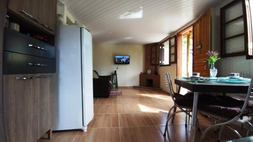 uma sala de estar com uma mesa e um frigorífico em Casa Verde da Floresta da Gávea em Visconde de Mauá