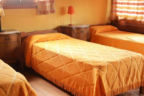 una habitación con dos camas con sábanas de color naranja en el Laberinto Gesell de Villa Gesell