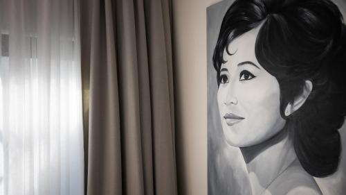 a painting of a woman on a wall next to a curtain at Shintana Saya La Maison in Siem Reap
