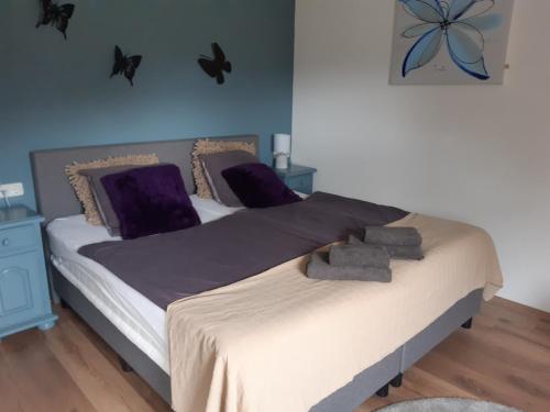 1 dormitorio con 1 cama grande con almohadas moradas en B&B Bourgondisch Lomm en Lomm