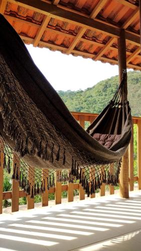 a hammock under a roof with a mountain in the background at Casa Verde da Floresta da Gávea in Visconde De Maua