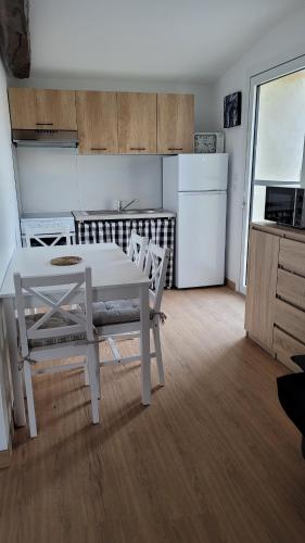 uma cozinha com uma mesa e cadeiras brancas e um frigorífico em Gite le Petit Doué em Noirlieu
