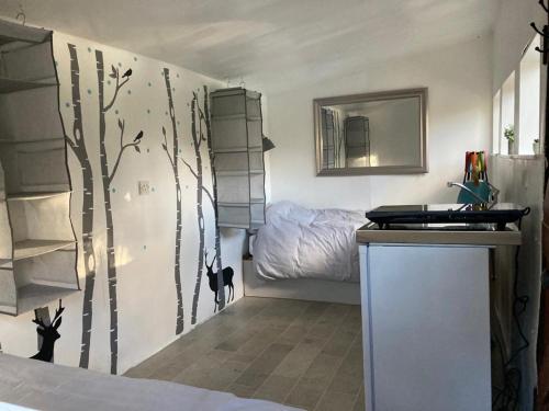 a bedroom with a tree mural on the wall at Fisherman's Cabin on the banks of the River Meon in Southampton