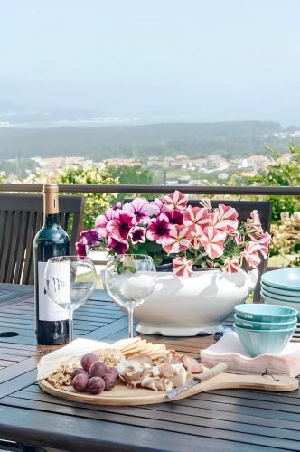 a table with a bowl of flowers and a bottle of wine at Casa Bela Vista de Moledo in Moledo