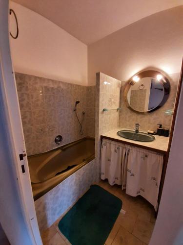 une salle de bain avec un lavabo, une baignoire et un miroir dans l'établissement La Caverne du Buisson, à Truffe