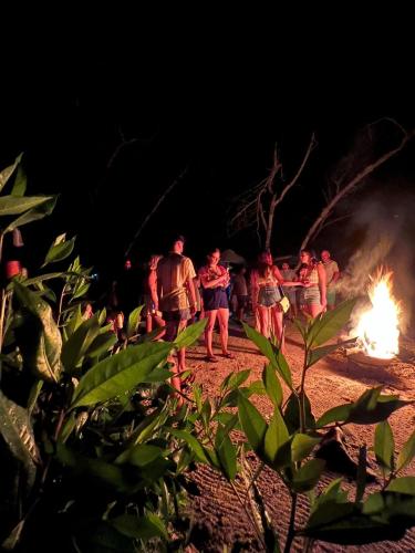 a group of people walking around a fire at night at Hostal Secreto in Isla Grande