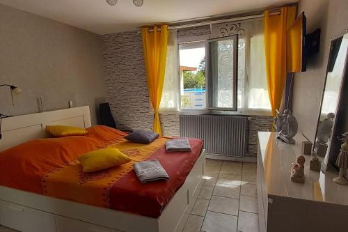 um quarto com uma cama com lençóis laranja e almofadas amarelas em proche Paris maison dans village près de reims 