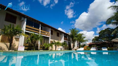 uma piscina em frente a um edifício com palmeiras em Apart Hotel Portal Do Atlântico - Portal Hotéis em Porto Seguro