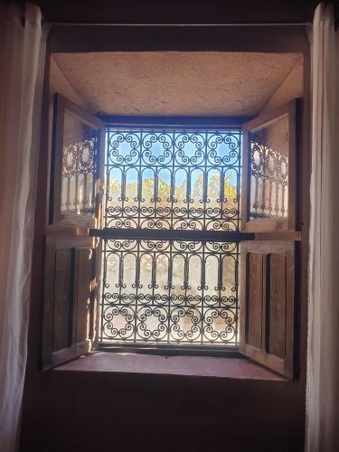 an open door with a window with a iron gate at Maison d'hôtes IZZA in Kalaat MGouna