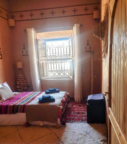 a bedroom with a bed and a window at Maison d'hôtes IZZA in Kalaat MGouna