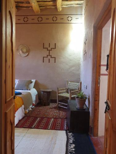a bedroom with a bed and a chair in a room at Maison d'hôtes IZZA in Kalaat MGouna