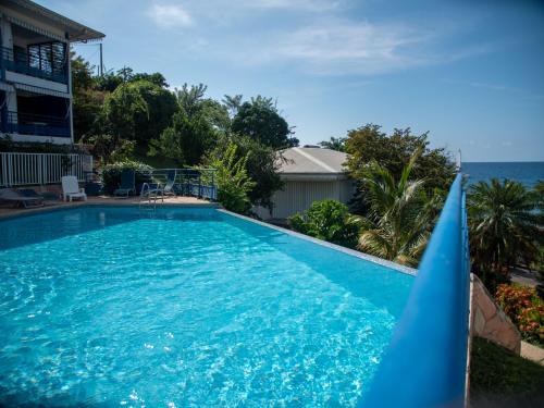 a blue swimming pool with the ocean in the background at Résidence Madicréoles in Le Carbet