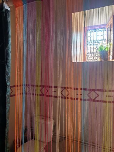 a room with a curtain with a toilet and a window at Maison d'hôtes IZZA in Kalaat MGouna