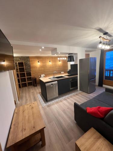 un salon avec un canapé et une cuisine dans l'établissement Duplex 12p St Sorlin D'arves résidence Odalys, à Saint-Sorlin-dʼArves