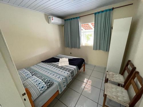 Habitación pequeña con cama y ventana en Casa Brisa do Mar Itapoá conforto à uma quadra da praia en Itapoa
