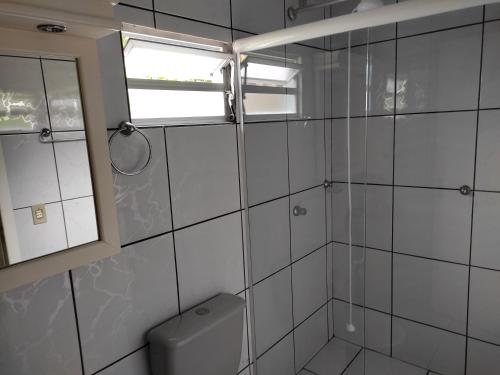 uma casa de banho com um chuveiro, um WC e uma janela. em Casa Brisa do Mar Itapoá conforto à uma quadra da praia em Itapoa