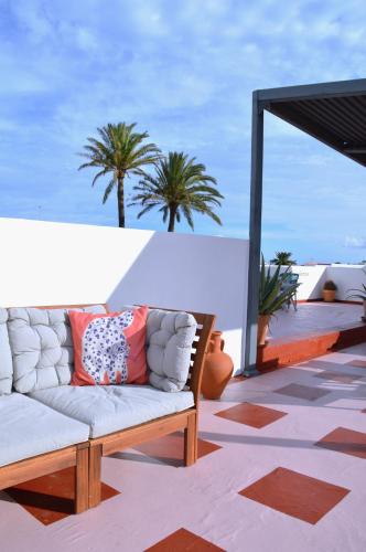 a couch on a patio with palm trees in the background at Villa Nestor in Ingenio