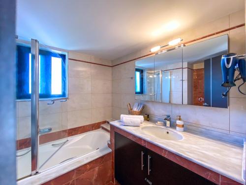bagno con vasca, lavandino, vasca e specchio di Rosalia House a Città di Rodi