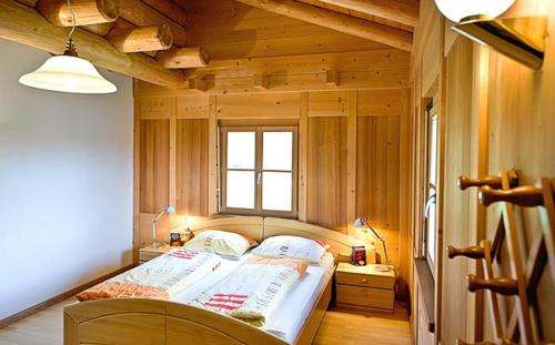 1 dormitorio con 1 cama en una habitación con paredes de madera en Appartements Karbon, en Seiser Alm