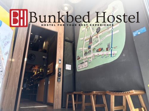 a sign for a building with two stools in front at Bunkbed Hostel in Makkasan