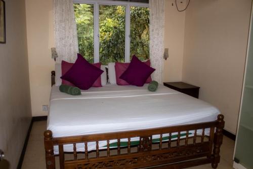 a bed with purple pillows in a room with a window at Eco Village Yoga Home in Digana