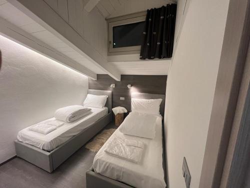 Una pequeña habitación con dos camas y un televisor. en Mansarda Angel's Home, en Ponte di Legno