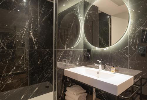 a bathroom with a sink and a shower with a mirror at KYRIAD Tours Sud - Ballan Mire in Ballan-Miré