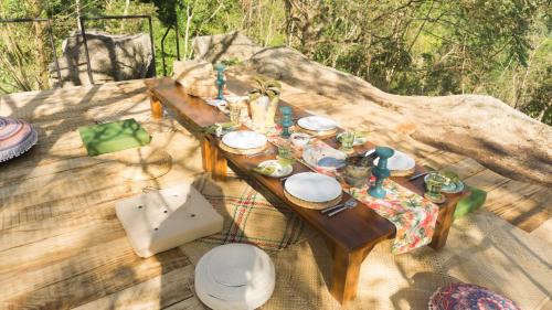einem Holztisch mit Tellern und Geschirr darauf in der Unterkunft Araliya Villa by Ella Nine Peaks in Ella