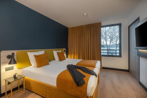 ein Schlafzimmer mit einem großen Bett und einem großen Fenster in der Unterkunft KYRIAD Tours Sud - Ballan Mire in Ballan-Miré