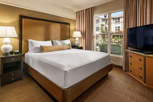 a bedroom with a large bed and a flat screen tv at Sonesta Suites Scottsdale Gainey Ranch in Scottsdale