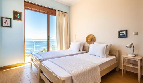 two beds in a room with a view of the ocean at Iris Villas Lefkada - Karavi Villa in Évyiros