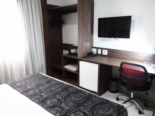 a hotel room with a desk and a bed and a chair at Nobile Inn Dutra Rio De Janeiro in São João de Meriti