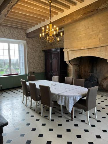 une salle à manger avec une table et des chaises et une cheminée dans l'établissement La Grande Rocque, à Airel