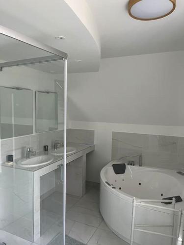 La salle de bains blanche est pourvue d'une baignoire et de deux lavabos. dans l'établissement La Grande Rocque, à Airel