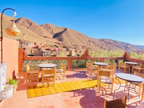 a patio with tables and chairs with mountains in the background at Hôtel Bia Besta in Boumalne