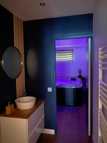 a bathroom with a sink and a tub with purple lighting at Détente & Spa in Villers-Allerand