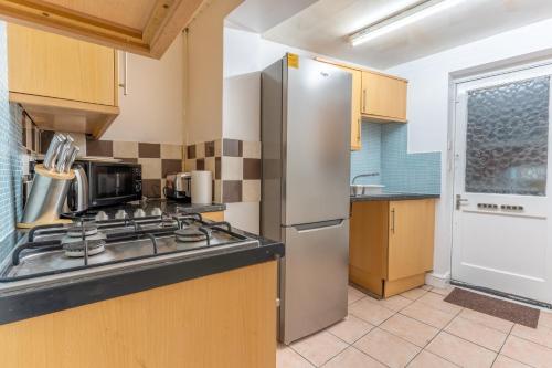 a kitchen with a stove and a refrigerator at "Furnished Rentals Direct" DominionHouse cul-de-sac Home for 6 people in Anfield near LFC, Goodison Park, Free Street Parking, Suits Travellers, contractors and Family, Near Football action and 10 minutes drive to Liverpool City Centre in Liverpool